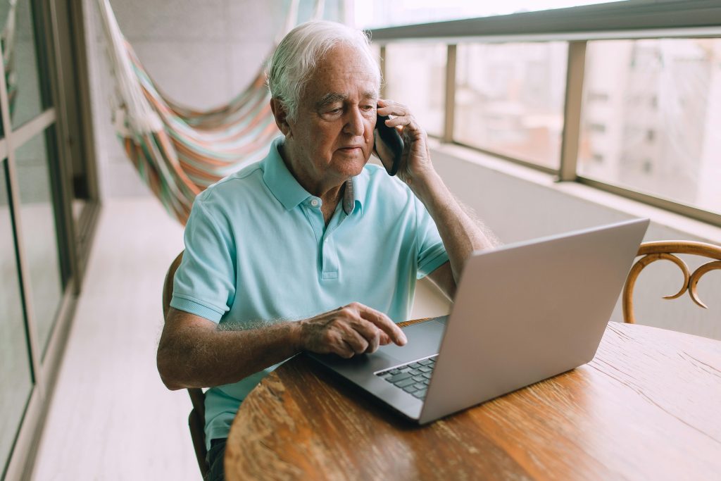 An Elderly Man with a Laptop and a Smartphone